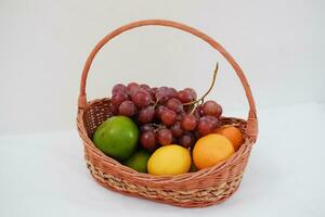 Fruits in a basket on a white background. Orange, grape, lemon. photo