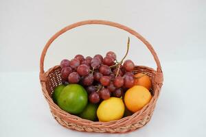 Fruits in a basket on a white background. Orange, grape, lemon. photo