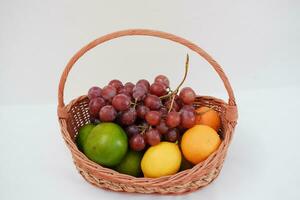 frutas en un cesta en un blanco antecedentes. naranja, uva, limón. foto