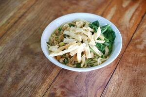 Fried noodle in white bowl on wooden table photo