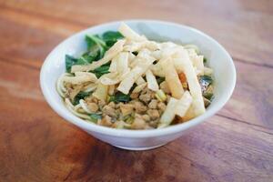 Fried noodle in white bowl on wooden table photo