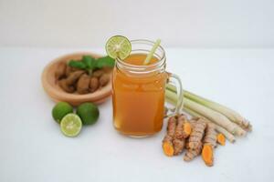 Fresh ginger and lemon juice in a glass jar with ginger roots on white background. photo