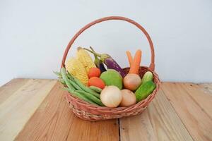 Vegetables in a basket on wooden background. Healthy food concept. photo