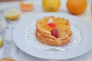 Fruta tarta en un blanco plato con limones y mandarinas foto