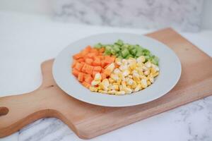 congelado vegetales en un blanco plato en un blanco mármol mesa. foto