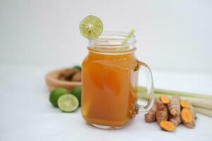 Fresh ginger and lemon juice in a glass jar with ginger roots on white background. photo