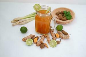 Fresh ginger and lemon juice in a glass jar with ginger roots on white background. photo