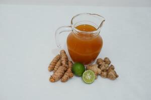 Ginger juice in a jug and fresh ginger on a white background photo