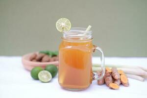 Fresh ginger and lemon juice in a glass jar with ginger roots on white background. photo