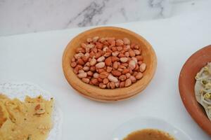 Close up of peanuts in a wooden bowl on a white background. photo