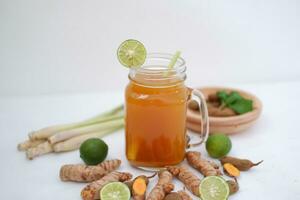 Fresh ginger and lemon juice in a glass jar with ginger roots on white background. photo