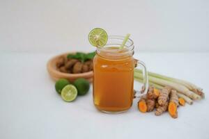 Fresh ginger and lemon juice in a glass jar with ginger roots on white background. photo