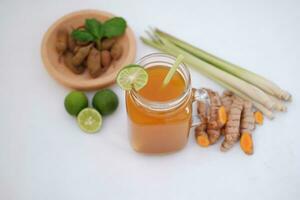 Fresh ginger and lemon juice in a glass jar with ginger roots on white background. photo