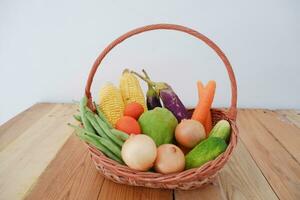 Vegetables in a basket on wooden background. Healthy food concept. photo