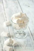 Glass bowl of marshmallows on the wooden background photo