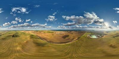 aerial hdri 360 panorama from great height or bird's eye view over plains, hills  and flooded quarry for sand extraction mining with sky and clouds in equirectangular spherical seamless projection photo