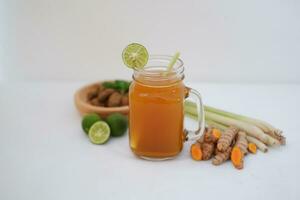 Fresh ginger and lemon juice in a glass jar with ginger roots on white background. photo