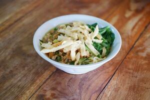 Fried noodle in white bowl on wooden table photo