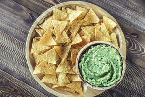 Guacamole with tortilla chips on the wooden tray photo