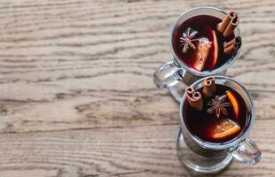 Two glasses of mulled wine on the wooden background photo