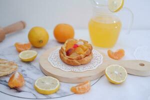 Homemade lemon tart with fresh fruit and orange juice on white background photo