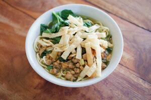 Fried noodle in white bowl on wooden table photo