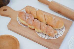 Bread donuts on the wooden table with wooden rolling pin. photo