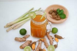 Fresh ginger and lemon juice in a glass jar with ginger roots on white background. photo