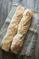 Two baguettes on the wooden background photo