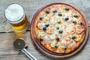 cocido Pizza con un vaso de cerveza foto