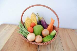 Vegetables in a basket on wooden background. Healthy food concept. photo