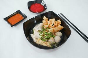 a bowl of meatball soup with chopsticks and chili sauce photo