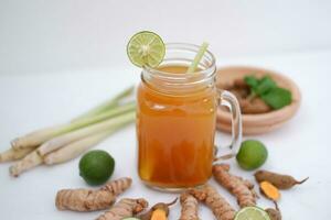 Fresh ginger and lemon juice in a glass jar with ginger roots on white background. photo