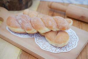 Bread donuts on the wooden table with wooden rolling pin. photo