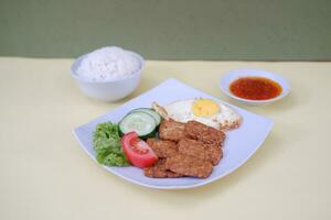 Fried tempeh cutlet with rice and fried egg on white plate photo