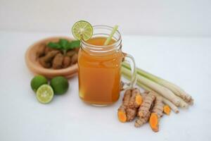 Fresh ginger and lemon juice in a glass jar with ginger roots on white background. photo