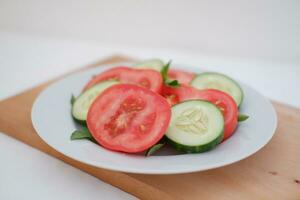 Cucumber and tomato slices on a plate on a white background photo