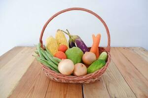 Vegetables in a basket on wooden background. Healthy food concept. photo