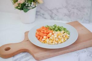 congelado vegetales en un blanco plato en un blanco mármol mesa. foto