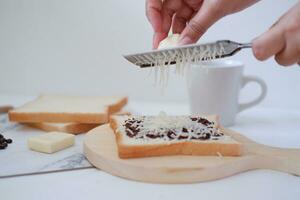 Woman's hands making toast with butter and chocolate on white background. photo