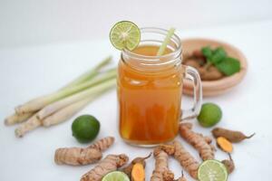 Fresh ginger and lemon juice in a glass jar with ginger roots on white background. photo