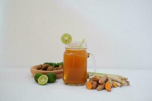 Fresh ginger and lemon juice in a glass jar with ginger roots on white background. photo