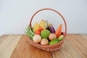 Vegetables in a basket on wooden background. Healthy food concept. photo