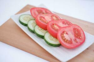Cucumber and tomato slices on a plate on a white background photo