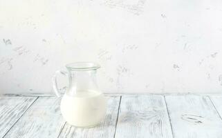 Jug of milk on the wooden background photo