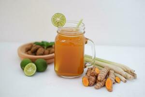 Fresh ginger and lemon juice in a glass jar with ginger roots on white background. photo