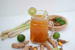 Fresh ginger and lemon juice in a glass jar with ginger roots on white background. photo