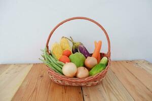 Vegetables in a basket on wooden background. Healthy food concept. photo