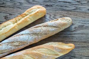 Three baguettes on the wooden background photo