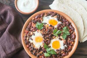 Bowl of chipotle bean chili with baked eggs photo